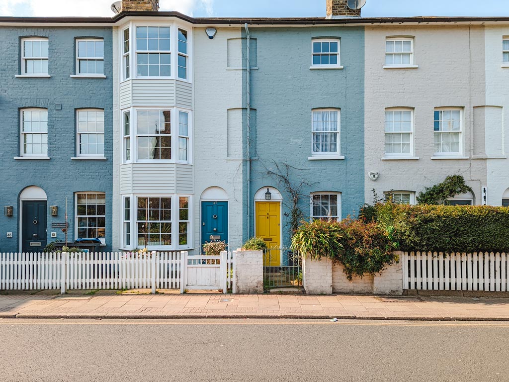 Row of blue and white terraced homes on street in London.