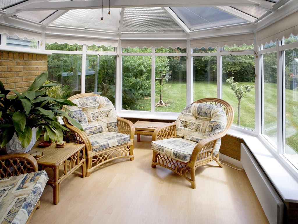 Interior view of conservatory with wicker seating and view of garden.
