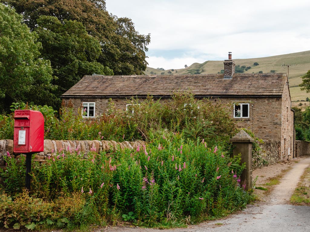 British country house in Peak District with red postbox near street.