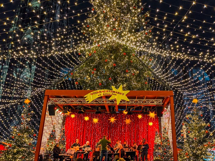 Cologne Christmas market stage at night with illuminated Christmas tree.