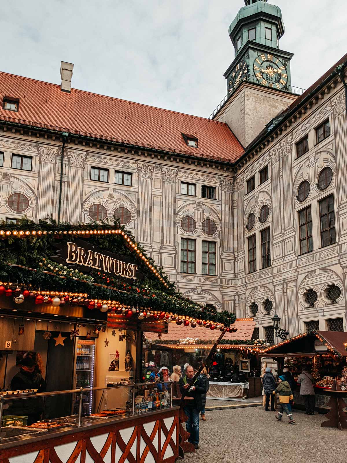 Courtyard German Christmas market in Munich with stall serving bratwurst.