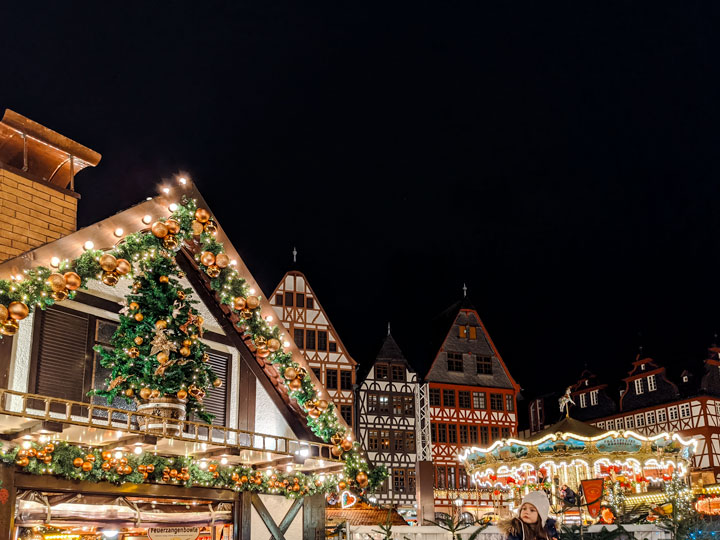 Frankfurt German Christmas Market at night with chalet and carousel.