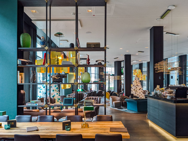 Table and bookshelf in lobby of Motel One Frankfurt hotel lobby.