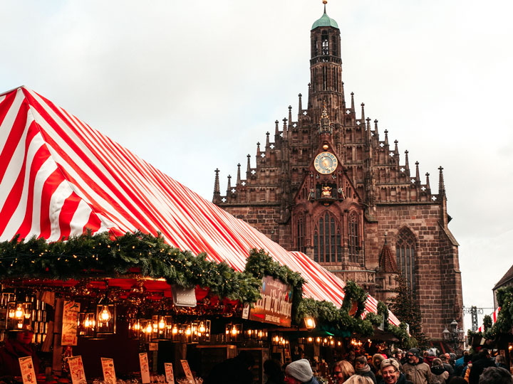 Nuremberg Christmas market red and white striped roof with cathedral in distance.