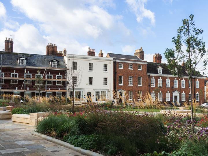 Row of expensive houses in Gloucester, UK with garden in foreground.