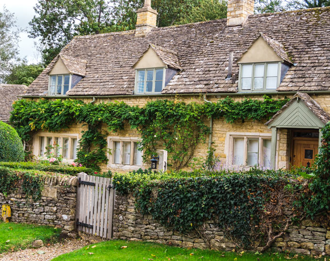 Traditional Cotswolds cottage in Castle Combe with ivy on facade.