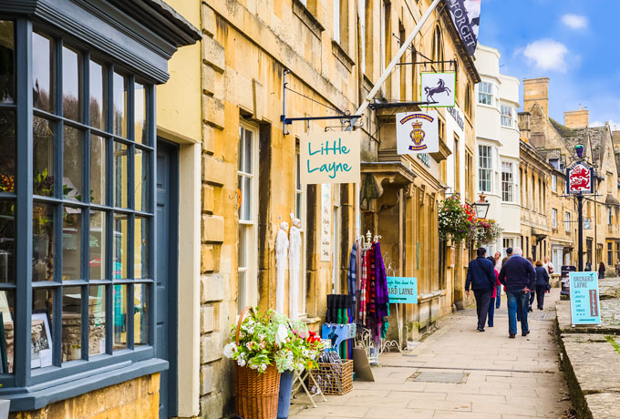 A Cotswolds day trip to Chipping Campden high street with shoppers walking down sidewalk.