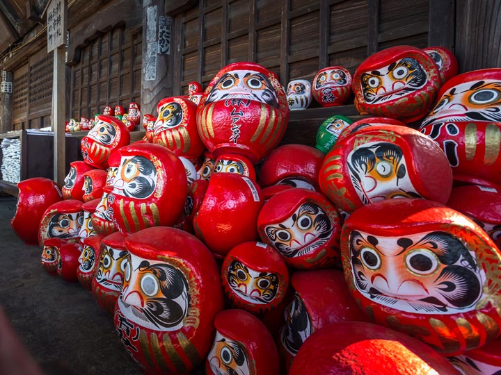 Stack of red daruma dolls at Japanese temple.