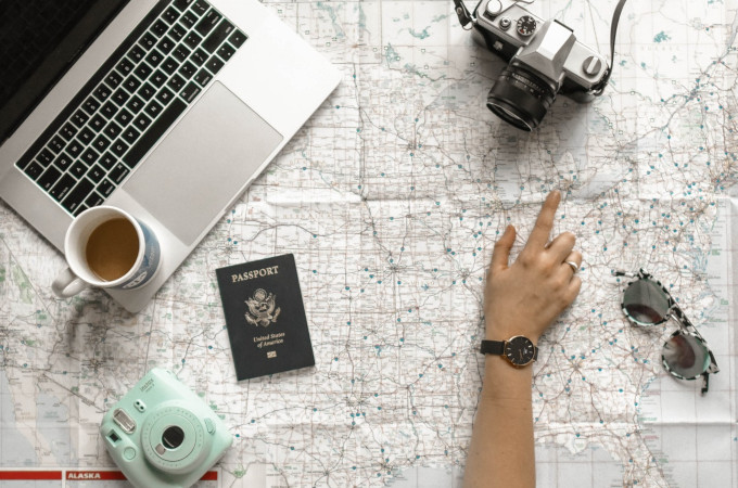 Woman's hand pointing to Michigan on map, deciding if she should move abroad.