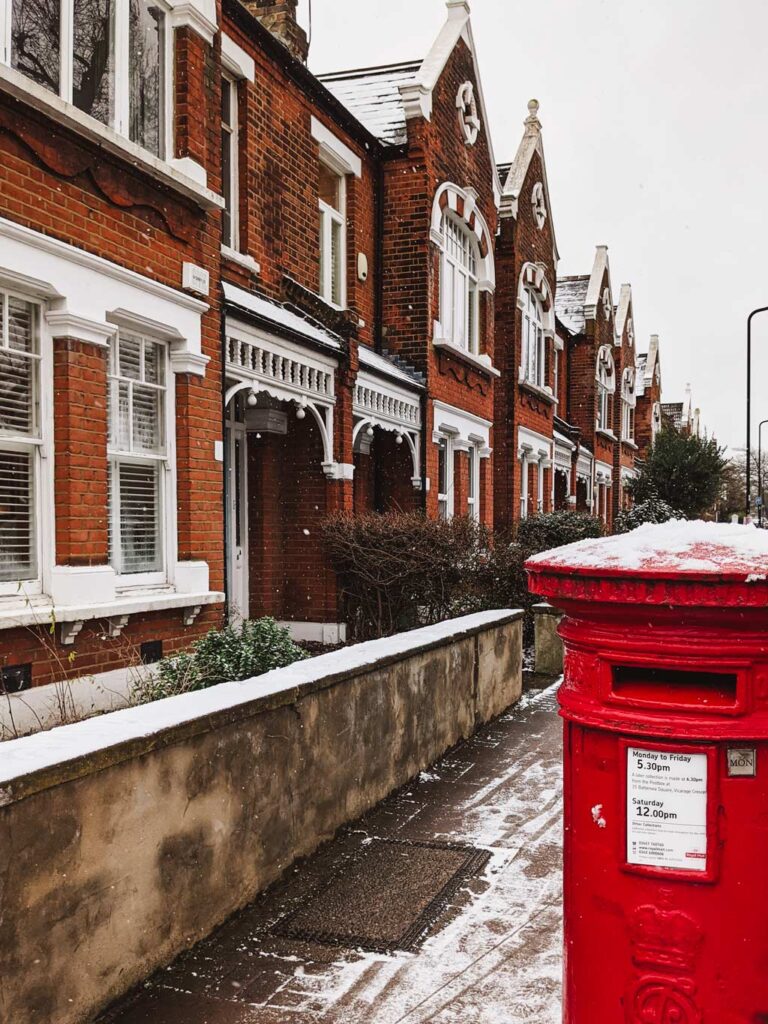UK residential street with red postbox covered in snow in foreground.