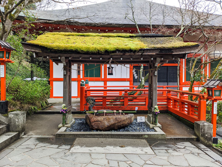 Kurama-dera purifying fountain with moss covered roof.