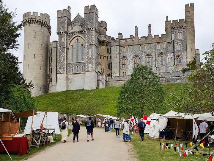 Medieval grey stone castle of Arundel with tents in front garden.