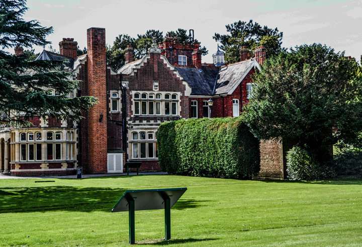 Brick front facade of Bletchley Park building with front garden.