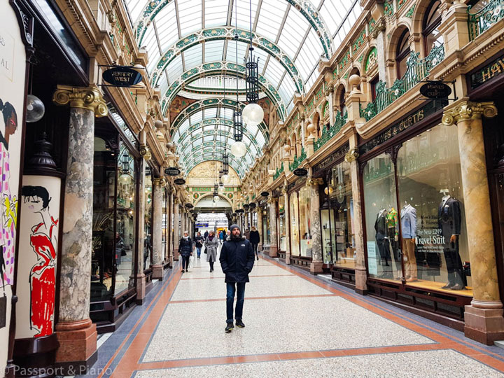 Man standing in covered Leeds shopping arcade with glass ceiling.