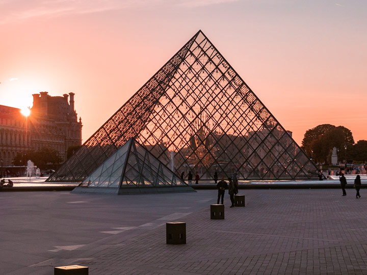 Louvre Pyramid with orange sunset in background.