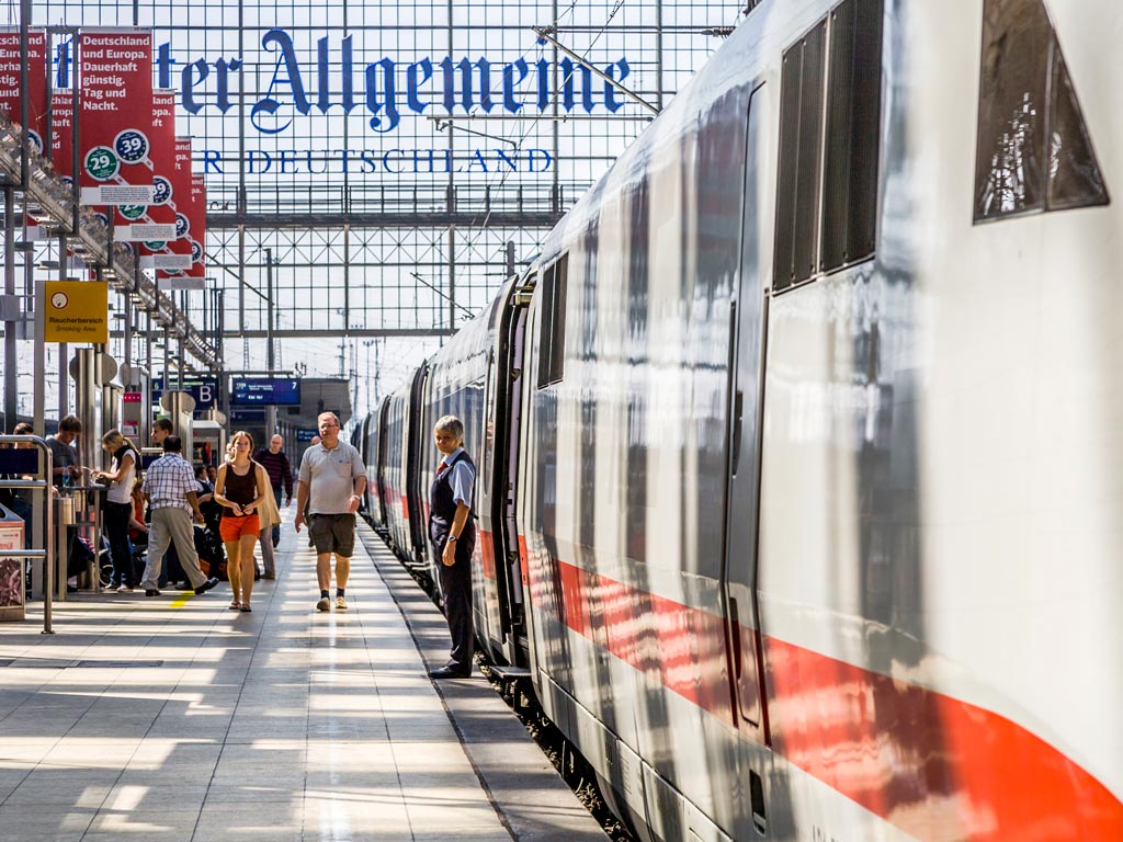 View down German train station platform, with several people using essential travel terms and phrases.