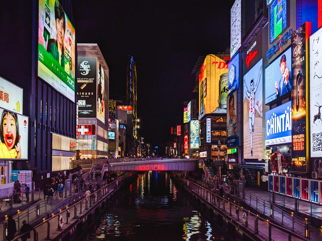 Nighttime view of Osaka Dotonbori canal lined with illuminated billboards.