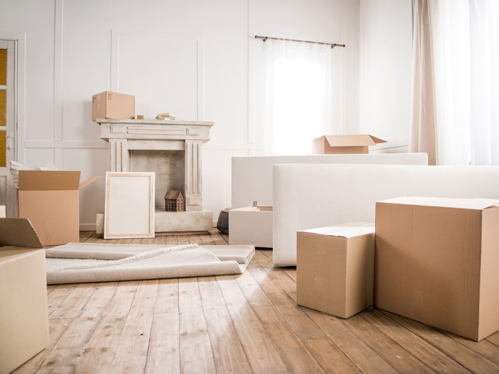 Living room with hardwood floors and white walls, and cardboard boxes on floor for moving out of the US.