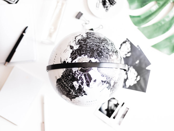 Overhead view of black and white globe, with photos and papers on desk.