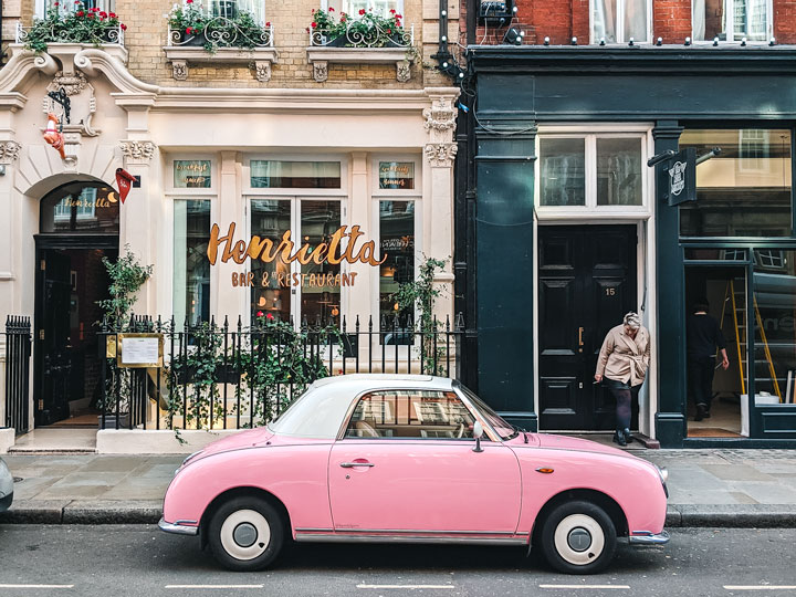 Pink classic car parked in front of white and blue buildings in London