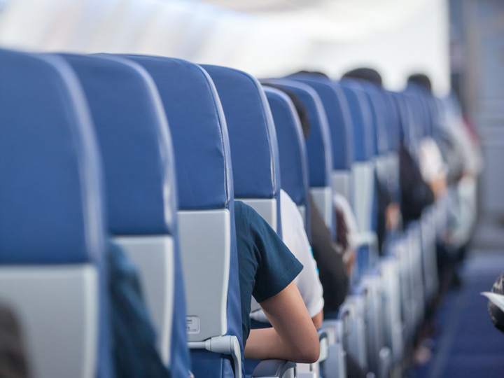 Aisle of blue airplane seats with passengers.