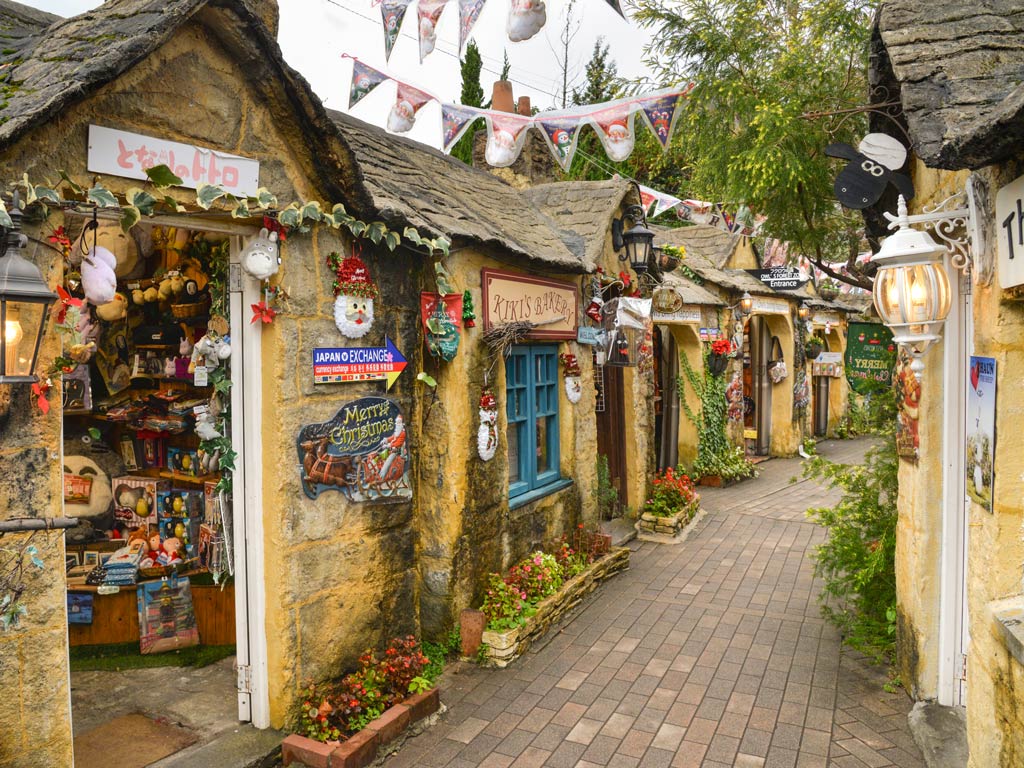 Cute yellow stone facades of shops on street in Yufuin.