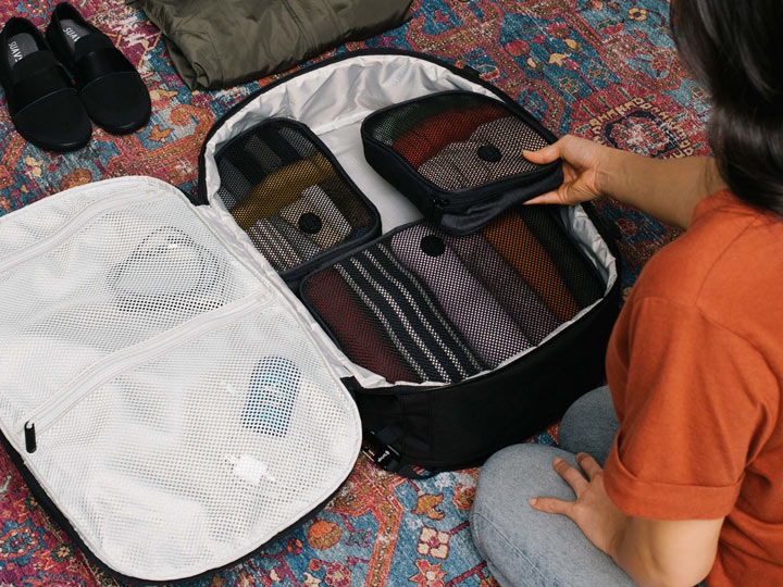 Girl packing Setout backpack with cubes, the best luggage for Japan travel to hold everything from your Japan travel checklist.