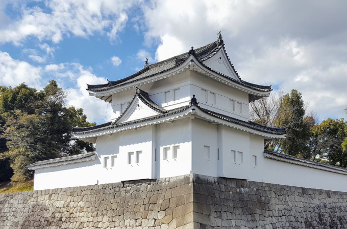 White castle on stone base against blue sky - Japan travel mistakes.