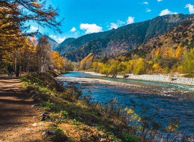 Two people hiking in Kamikochi Japan next to river.