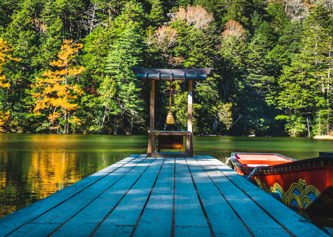 Myojin Pond Kamikochi Japan with red boat next to dock.