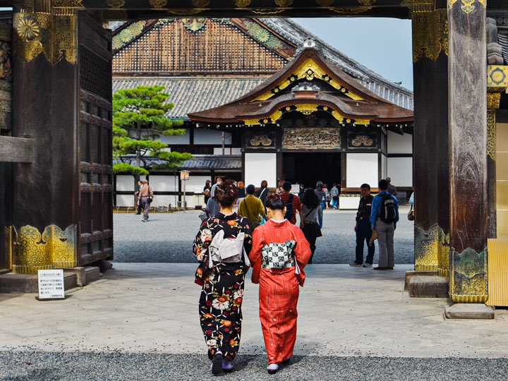 Two women in kimonos walking through gate of Nijo Castle.