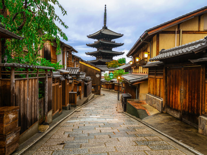 Old street in Kyoto lined with wooden buildings, with view of Kiyomizu pagoda at the end.