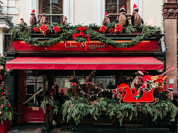 Christmas display with red sleigh and penguins at London restaurant.