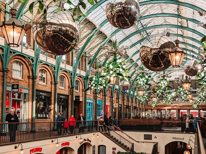 London Covent Garden Christmas market with large silver ornaments hanging from ceiling.