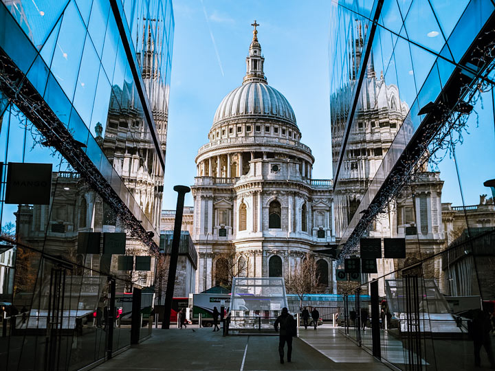 London St. Paul's Cathedral viewed from alley with glass walls reflecting building.