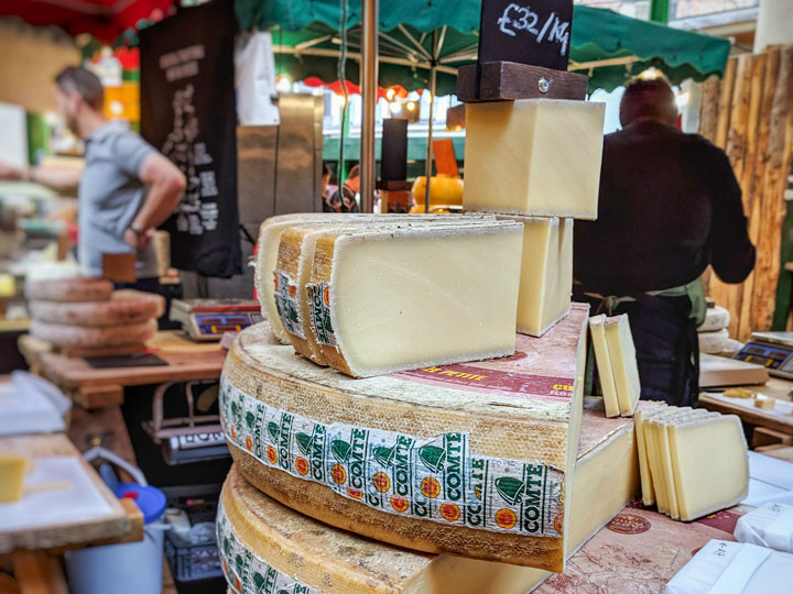 Wheels of cheese stacked up at London supermarket.