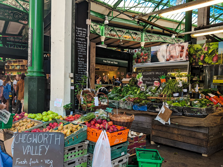 London grocery stores inside Borough Market with bins of produce and wooden crates of vegetables.