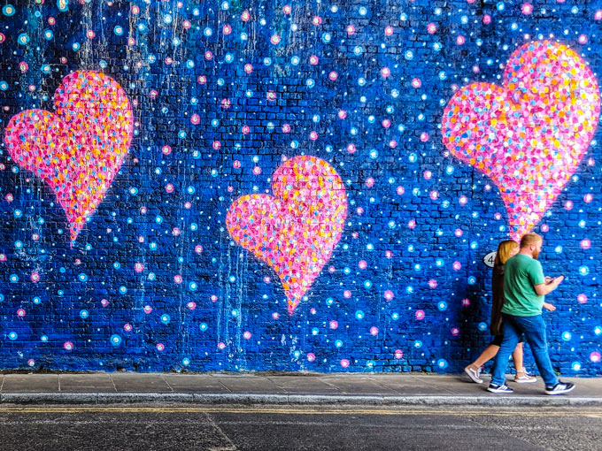 Couple walking in front of geart mural outside of Borough Market London.