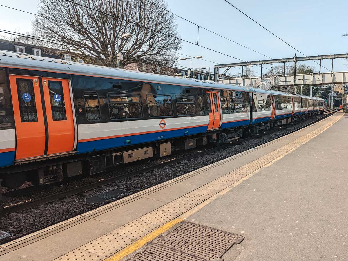 London Overground train cars stopped at outdoor platform.