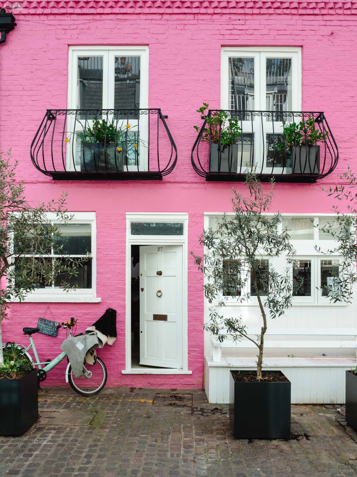 Famous Notting Hill Pink House from Love, Actually with white door and bike leaned against facade.