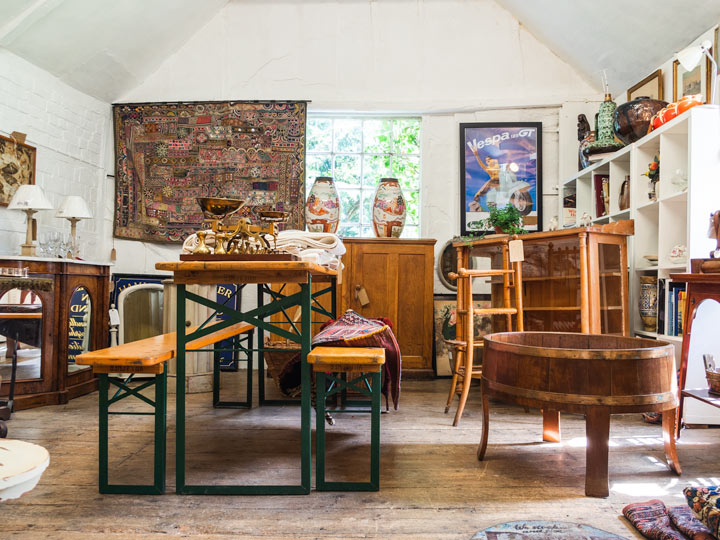 Bench table, wooden washbin, and assorted antique items in shop.