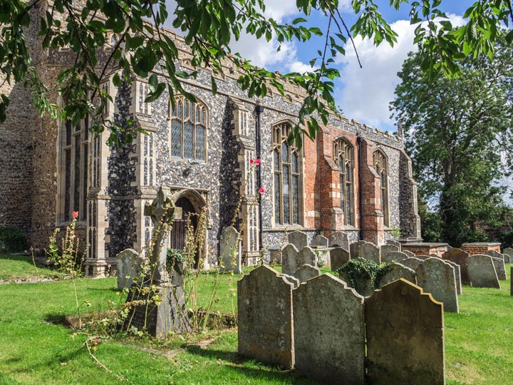 Churchyard with grave stones and church exterior with stained glass windows in Debenham England