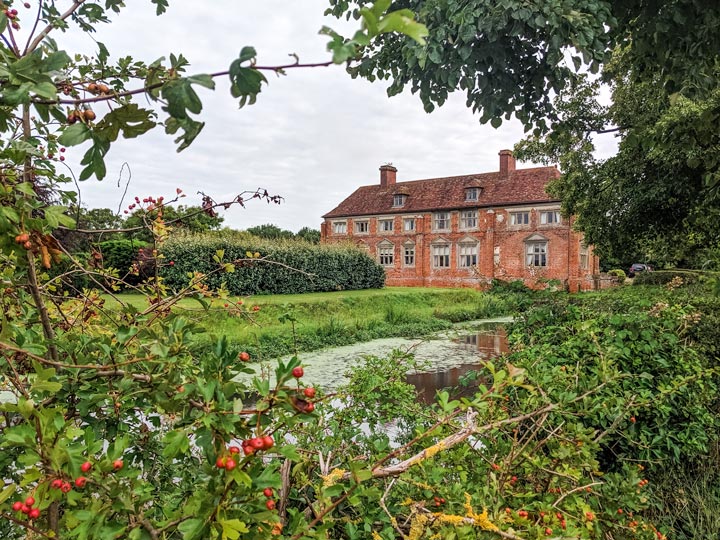 View of Kenton Hall Estate and moat through trees.