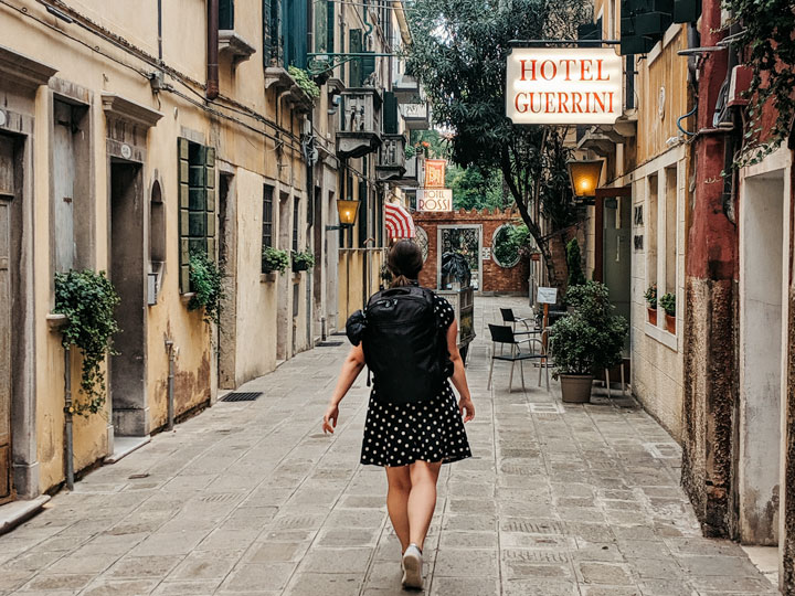 Girl walking down street wearing front loading travel backpack by Tortuga Setout.