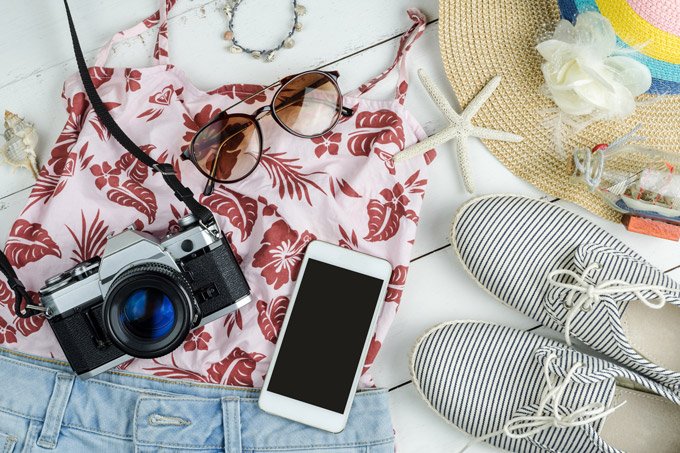 Flat lay of travel capsule wardrobe, including striped shoes, straw hat, and tank top.