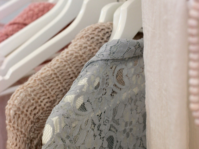 Close-up of pastel colored sweaters on white hangars.