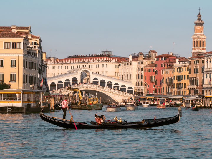 Sunset on Venice Grand Canal with gondola in foreground, one of the most Instagrammable places in Europe.