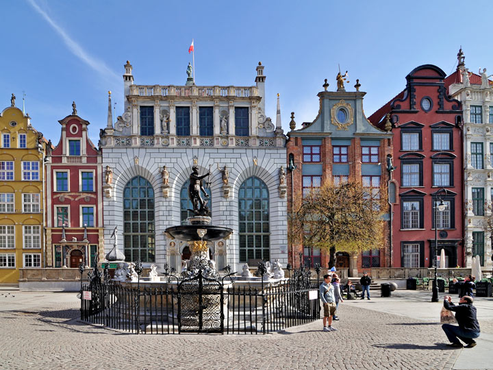 Gdansk town square with fountain and colorful buildings in background.