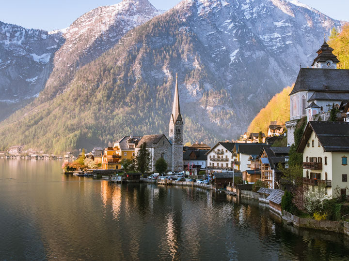 Panoramic view of Hallstatt village with lake in foreground and mountains in distance.