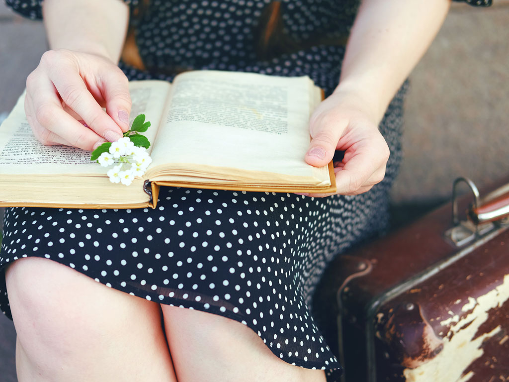 Woman in polka dot dress reading book about moving overseas after 30.